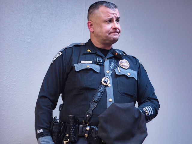 Captain AJ Rodriguez of the New Mexico State Police stands with an apologetic look on his face. He is wearing a duty uniform.