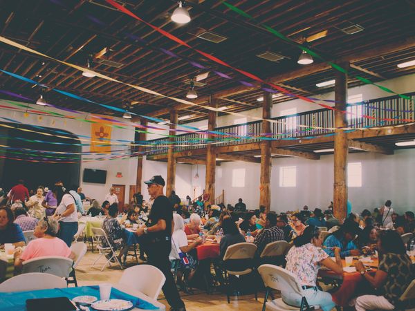 A view of the Dr. Saul Community Center, filled with streamers, and attendees sharing a meal
